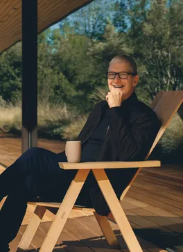 A host seated outdoors among the trees